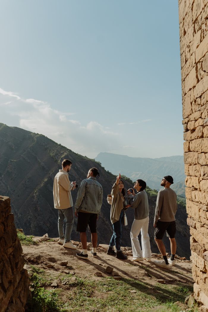 Group of friends exploring mountains, enjoying scenic views on a sunny day.